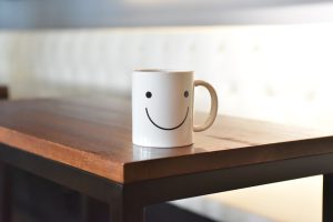 White mug with smiley face on a wooden table