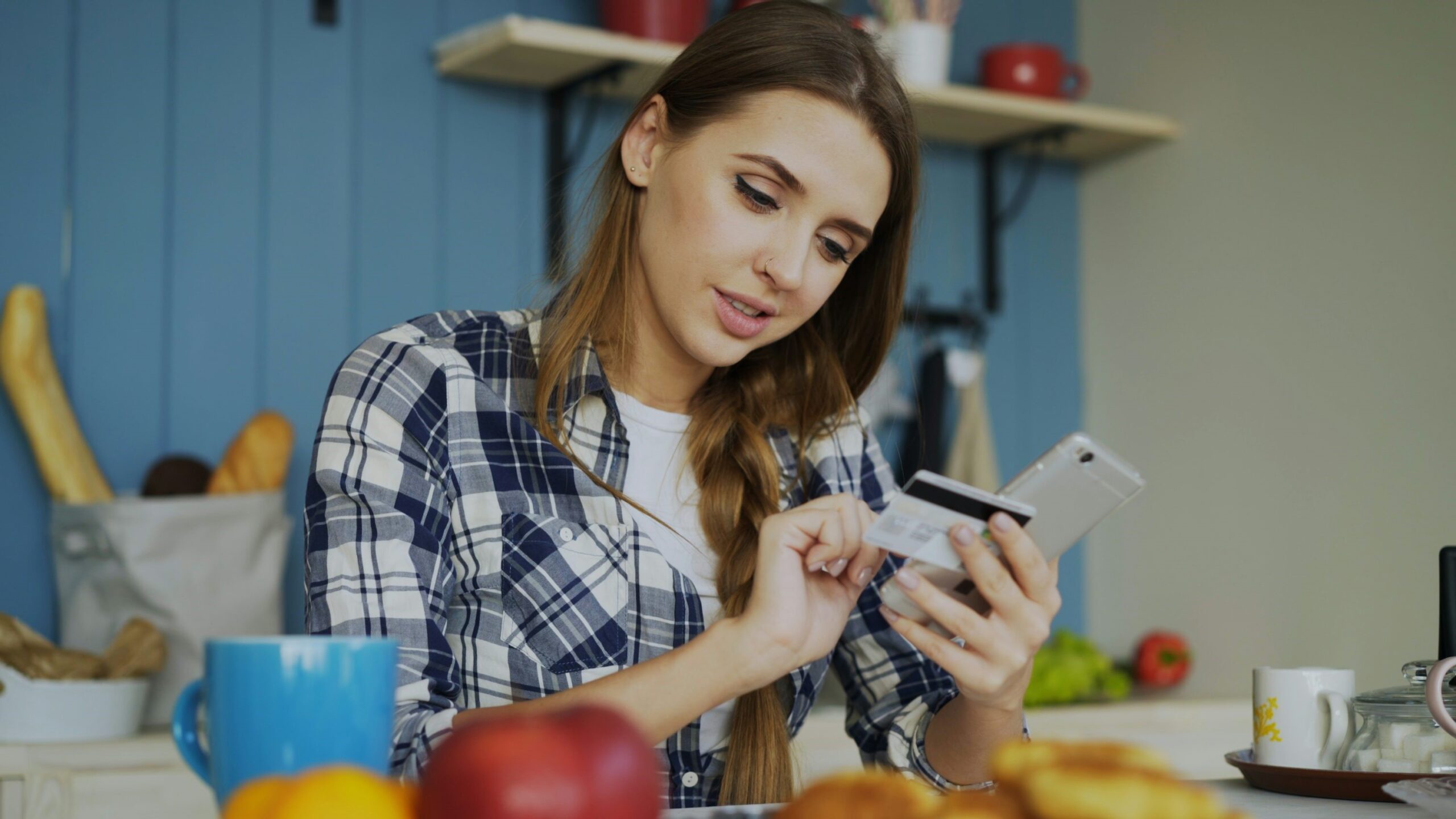 Young woman with mobile phone and credit card in hand.