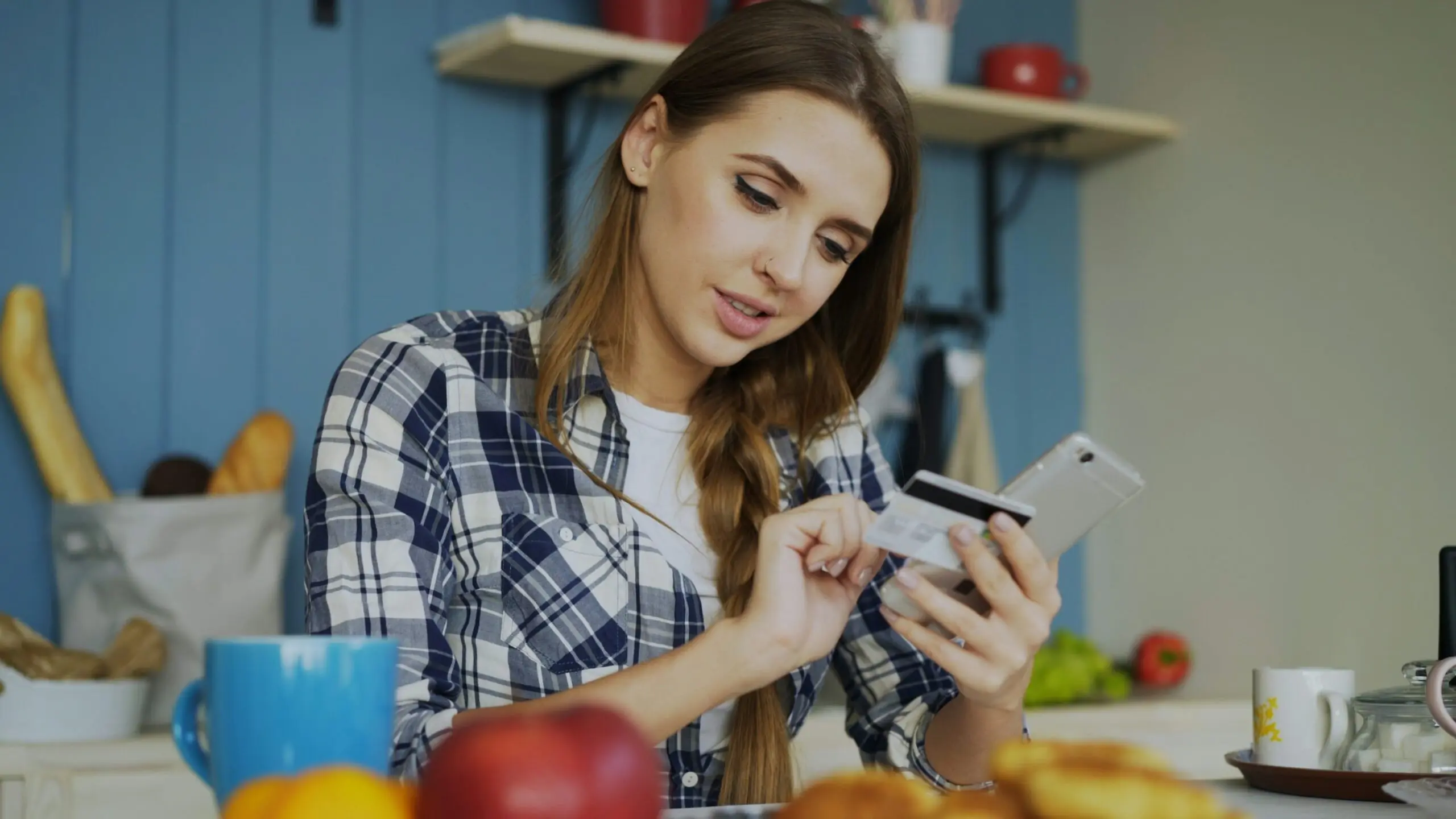Young woman with mobile phone and credit card in hand.