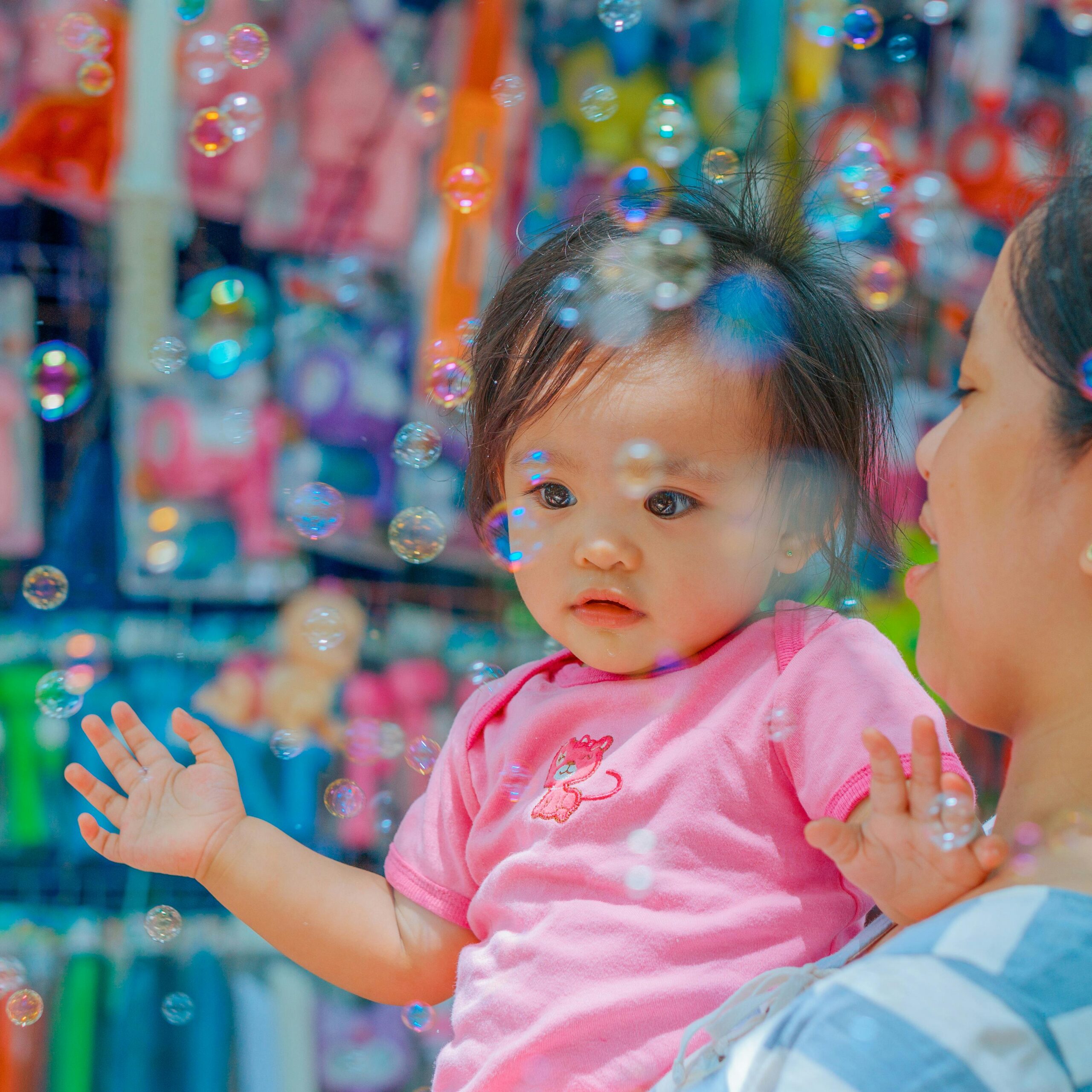 Small Asian child in her mother's arms, surrounded by bubbles