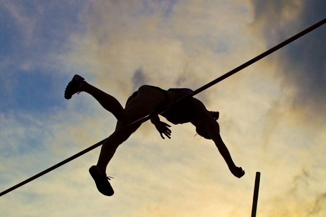 Woman jumping over a high bar